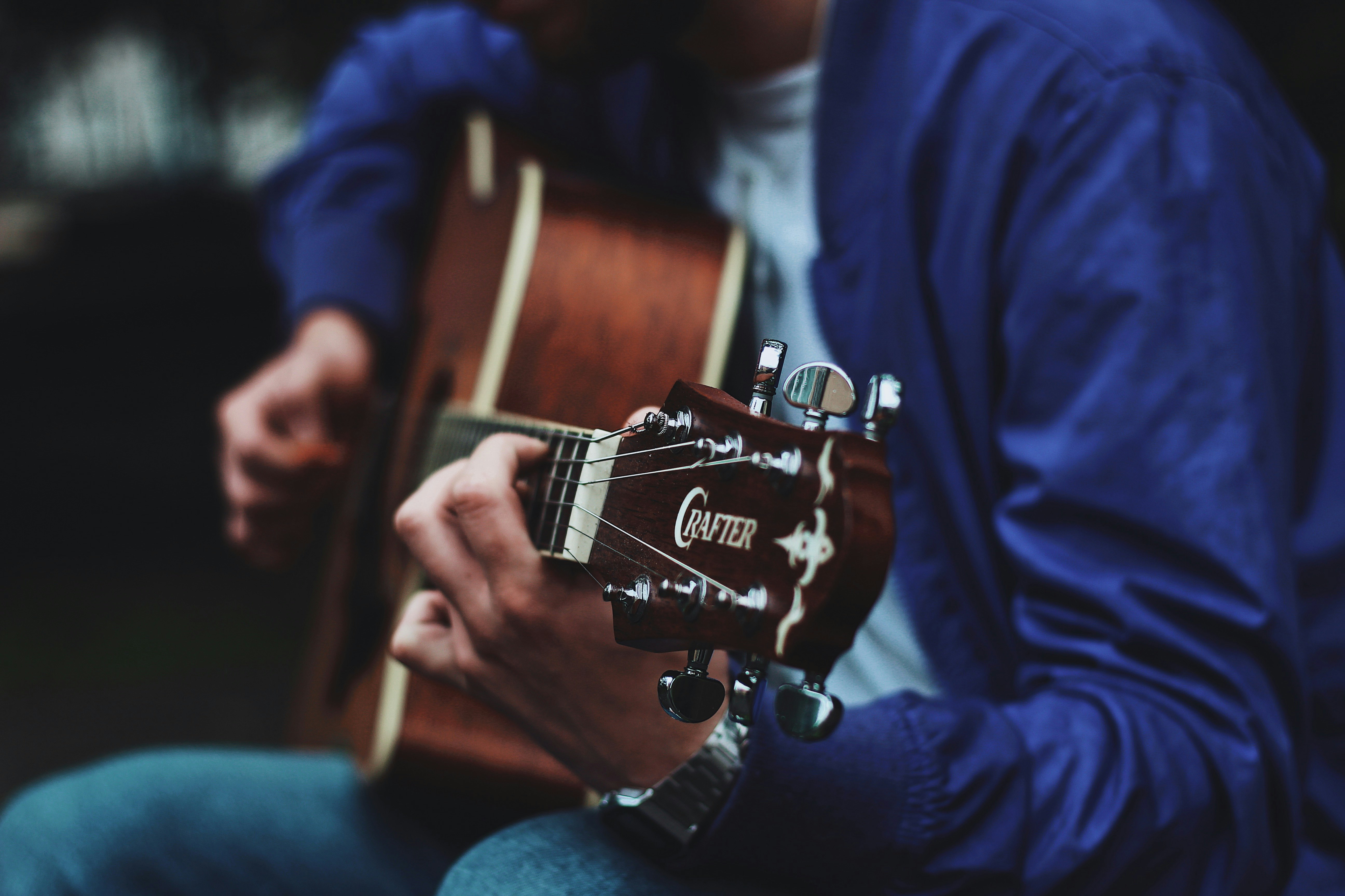 man playing brown guitar